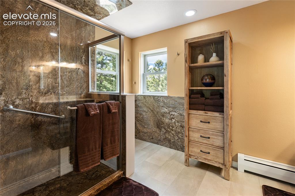 Image 18 of 40: Luxurious primary bath with a walk-in shower, granite surrounds, and dual-s
