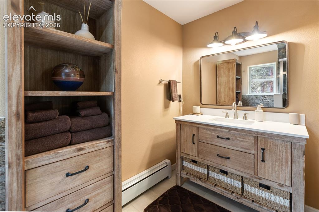 Image 19 of 40: Bathroom featuring a wood-finish vanity with a white countertop, an undermo