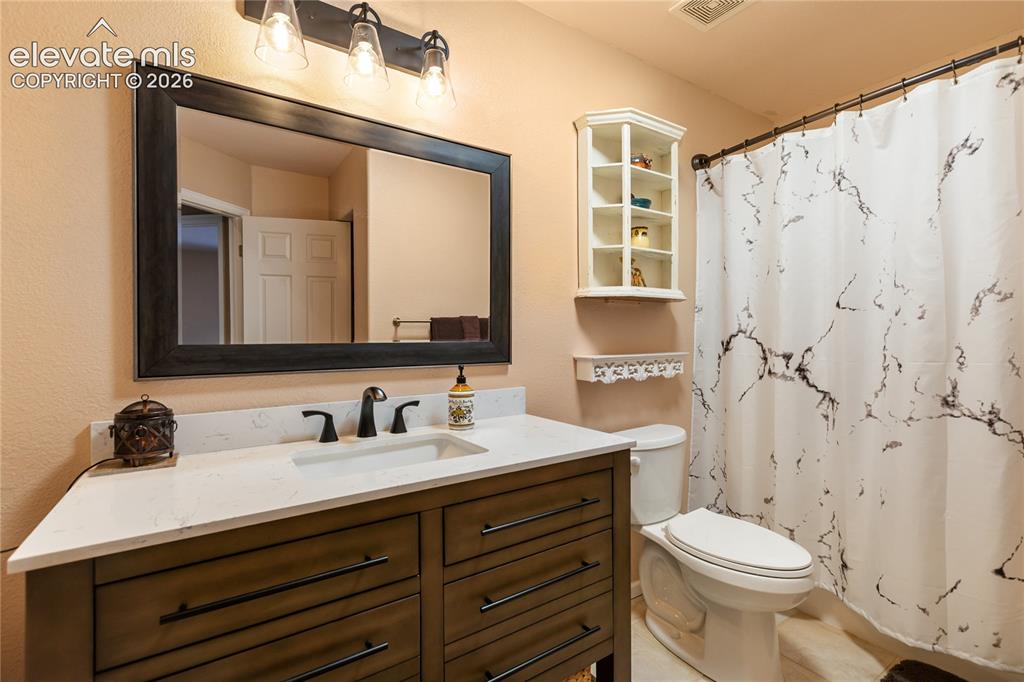 Image 22 of 40: Bathroom featuring a dark wood-finish vanity with a light countertop, under
