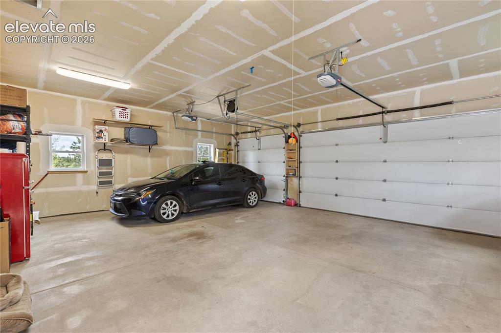 Image 27 of 40: Oversized three-car attached garage with plenty of room for vehicles, tools