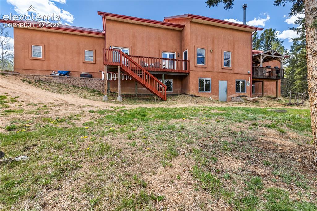 Image 36 of 40: Terracotta stucco exterior with red trim and multiple wooden decks