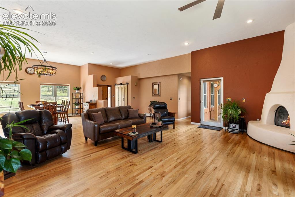 Image 6 of 40: Open concept living space featuring wood-finish flooring, a kiva-style fire