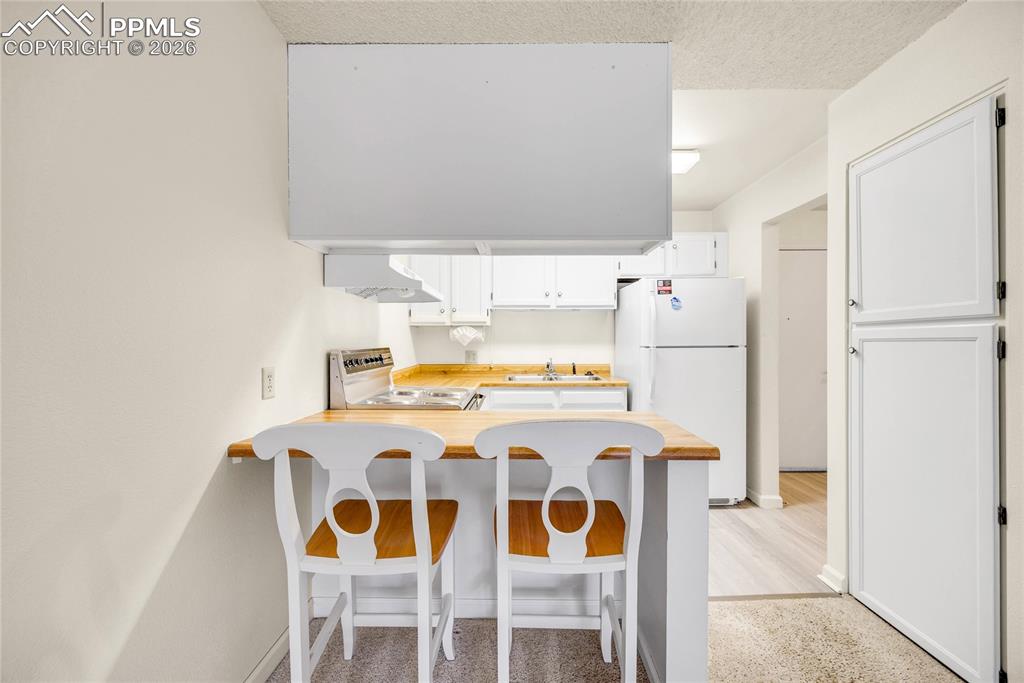 Image 2 of 17: Kitchen featuring white cabinetry, freestanding refrigerator, a breakfast b