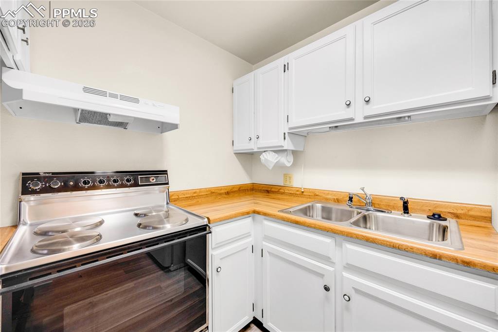 Image 4 of 17: Kitchen with range with electric stovetop, light countertops, white cabinet