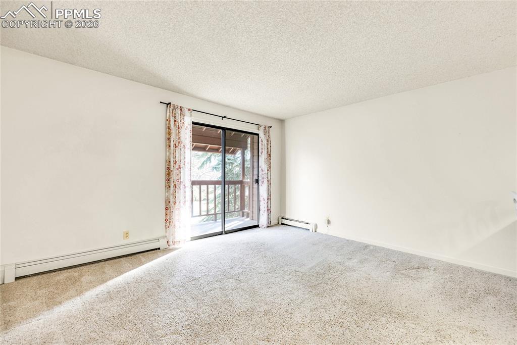 Image 6 of 17: Carpeted empty room featuring a textured ceiling and a baseboard heating un