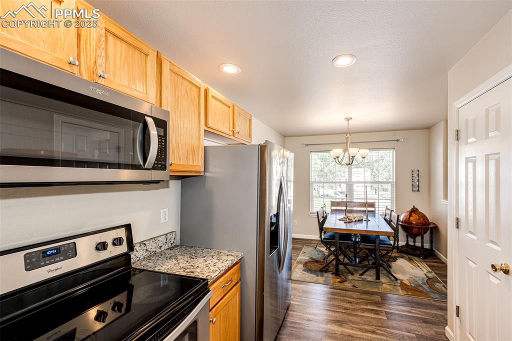 Image 10 of 34: Kitchen with stainless steel appliances, dark wood-style flooring, a chande