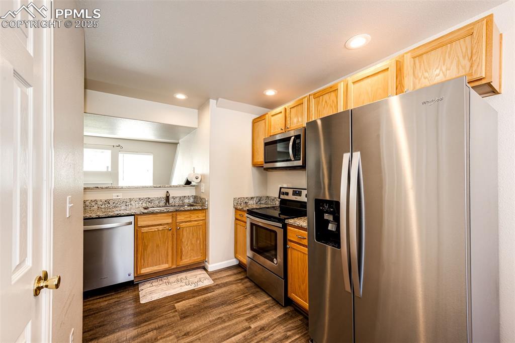 Image 13 of 34: Kitchen with stainless steel appliances, dark wood finished floors, stone c