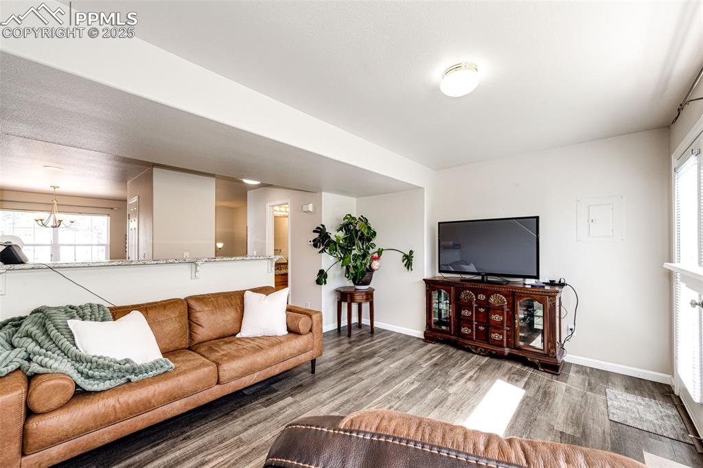 Image 6 of 34: Living area featuring wood finished floors, a chandelier, and plenty of nat