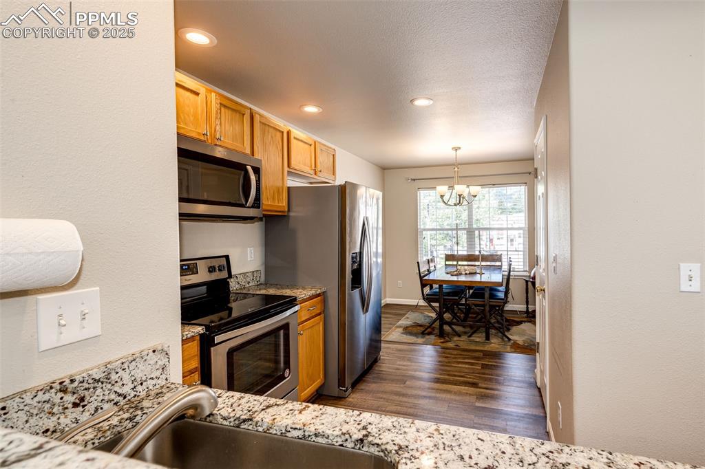 Image 8 of 34: Kitchen with stainless steel appliances, a chandelier, dark wood-style floo