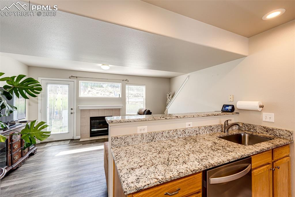 Image 9 of 34: Kitchen with dishwasher, a peninsula, wood finished floors, and brown cabin