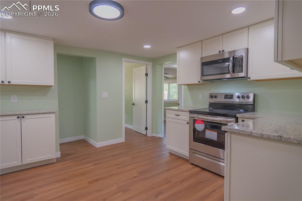 Image 10 of 18: Kitchen with stainless steel appliances, light stone counters, light wood-t