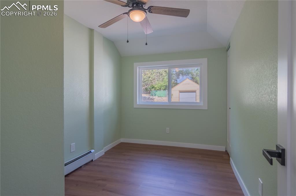 Image 15 of 18: Unfurnished room 2 featuring a baseboard heating unit, dark wood finished f