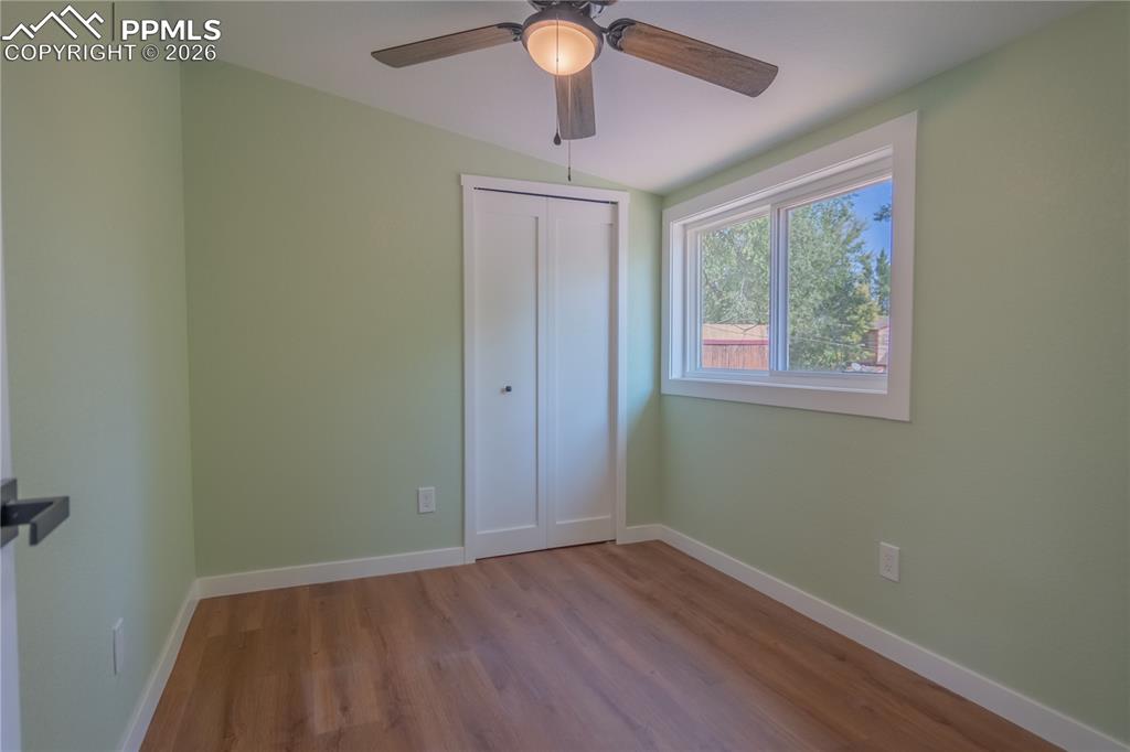Image 16 of 18: Unfurnished bedroom 3 with wood finished floors, a ceiling fan, vaulted cei