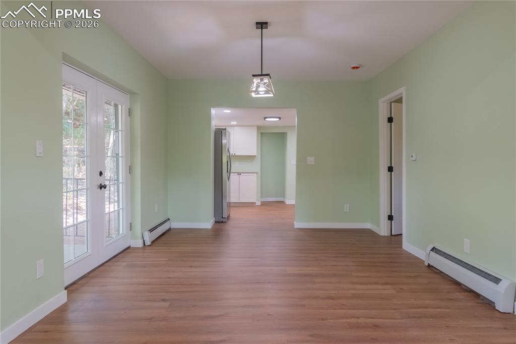 Image 7 of 18: Unfurnished dining area featuring baseboard heating, light wood-style floor
