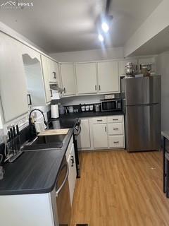 Image 10 of 30: Kitchen with stainless steel appliances, dark countertops, light wood-style