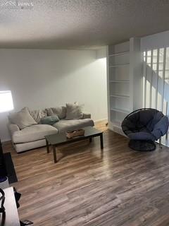 Image 7 of 30: Living room featuring a textured ceiling and wood finished floors