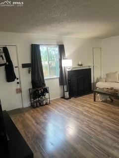 Image 8 of 30: Living room with wood finished floors, a fireplace, and a textured ceiling