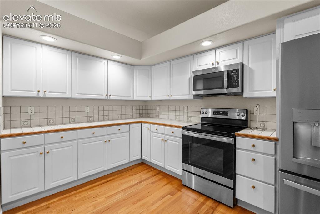 Image 10 of 41: Kitchen featuring extensive white cabinetry, wood-finish countertops, and a