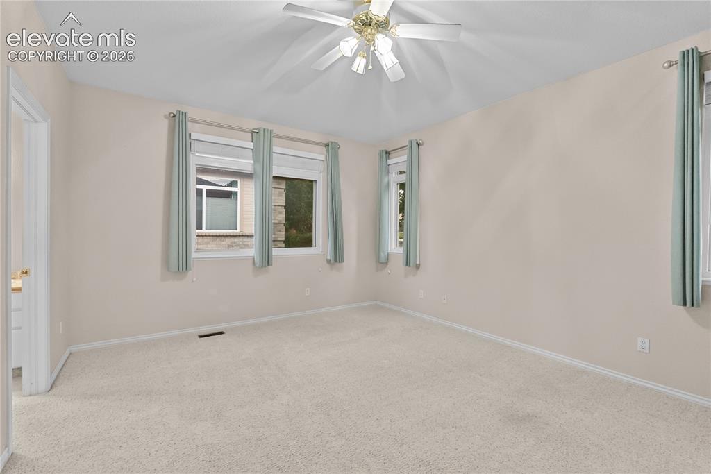 Image 12 of 41: Carpeted room with a ceiling fan light fixture, white trim, and light beige