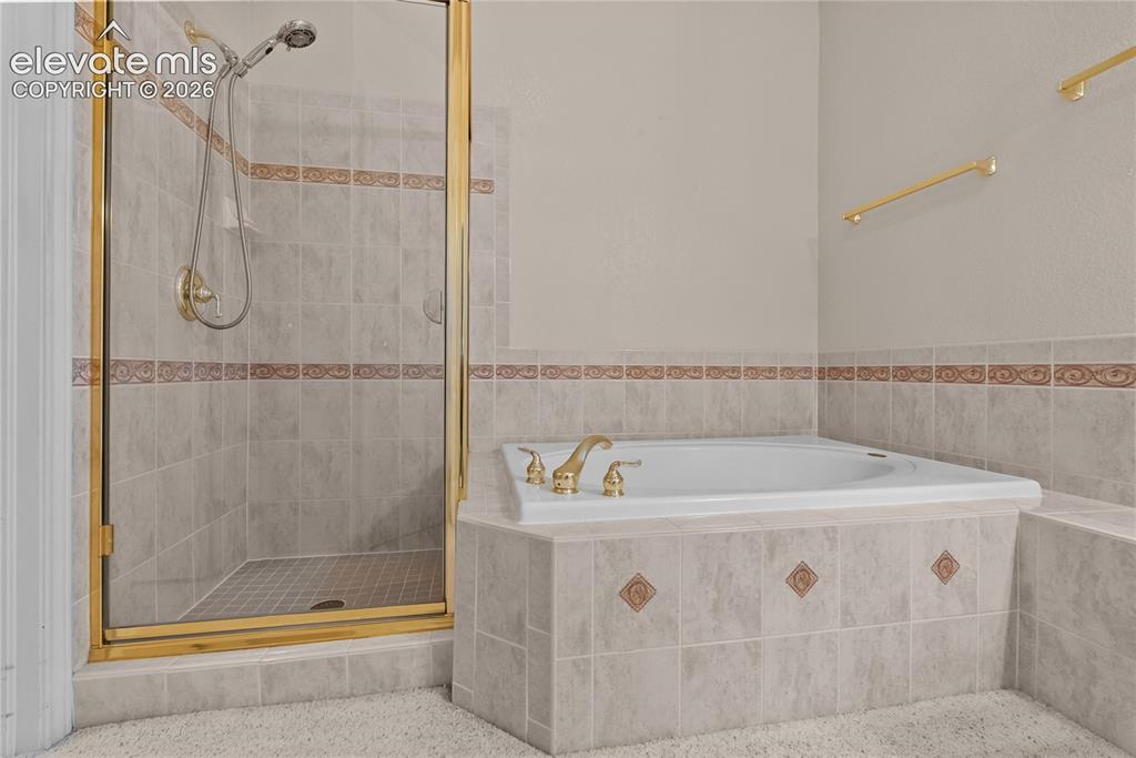 Image 15 of 41: Tiled walk-in shower with a gold-framed glass enclosure