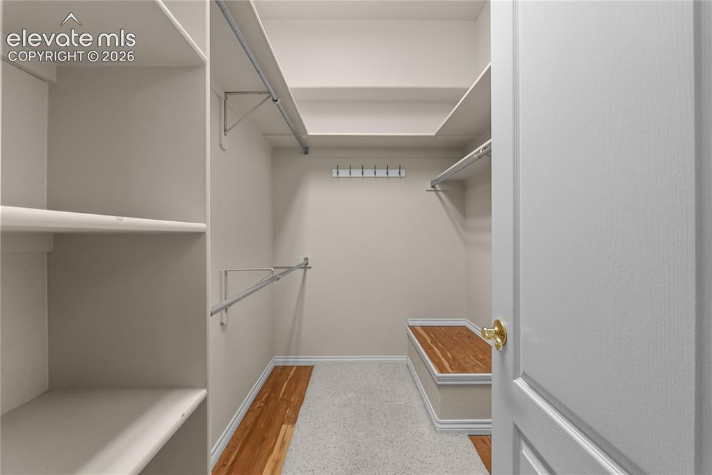 Image 16 of 41: Walk-in closet featuring extensive built-in shelving, multiple clothing rod