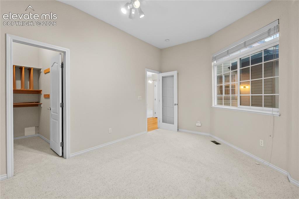 Image 20 of 41: Carpeted room with a large window featuring horizontal blinds