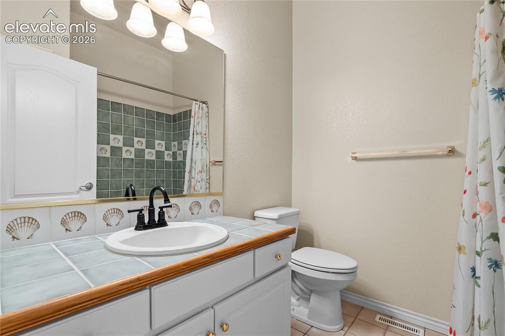 Image 21 of 41: Bathroom featuring a tile vanity countertop, integrated sink, and dark-fini