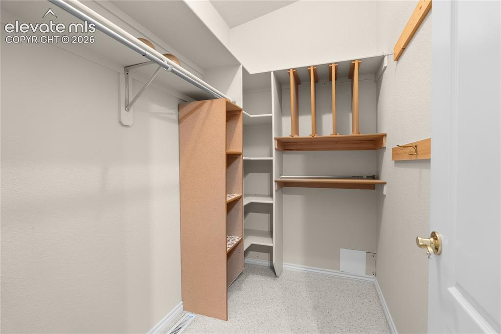 Image 24 of 41: Walk-in closet featuring white walls, multi-tiered shelving, built-in woode