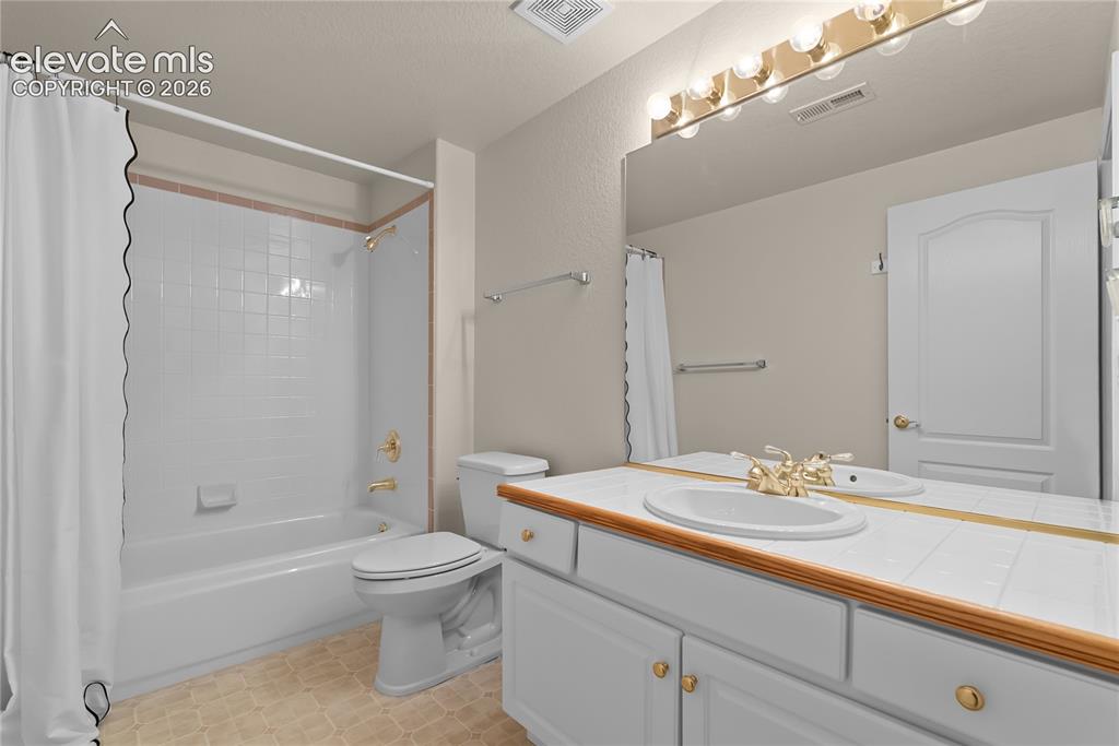 Image 35 of 41: Bathroom featuring a vanity with tile countertop, integrated sink, and gold