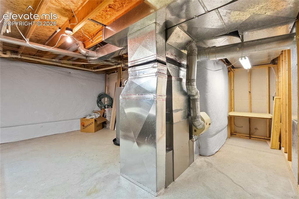 Image 36 of 41: Unfinished basement space featuring exposed wood joists, concrete flooring,