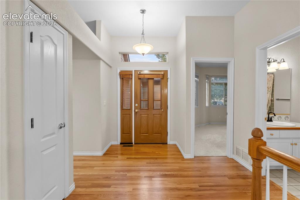 Image 6 of 41: Welcoming entry with hardwood flooring, a wood-paneled front door with side