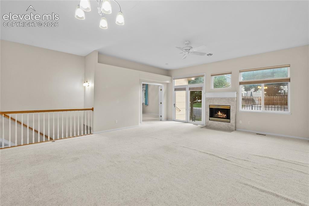 Image 7 of 41: Spacious room with a gas fireplace featuring a stone surround and mantel, a