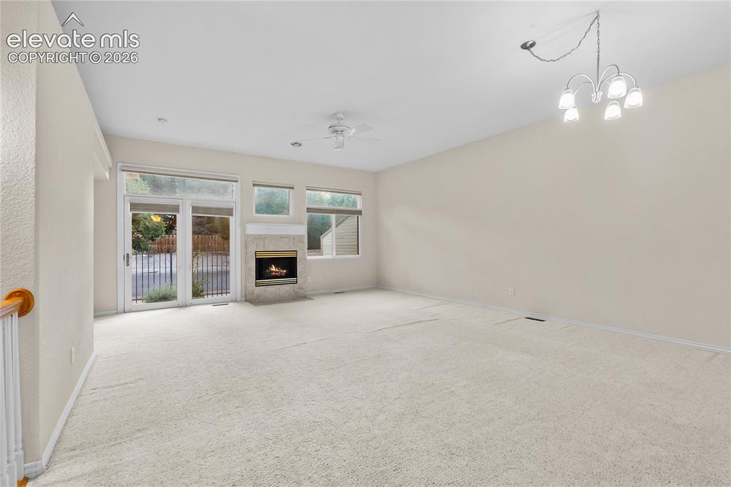 Image 8 of 41: Living space featuring light-toned carpet flooring, a stone-surround firepl
