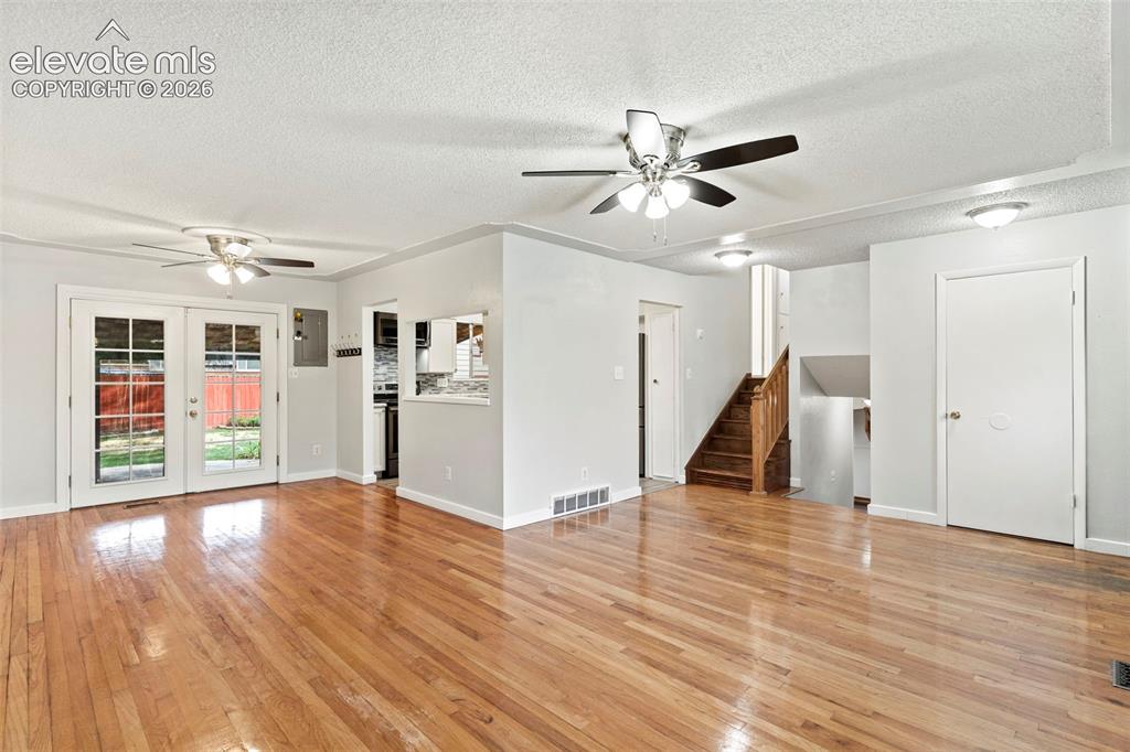 Image 12 of 36: Hardwood flooring, white painted walls, French doors, ceiling fans, and a v