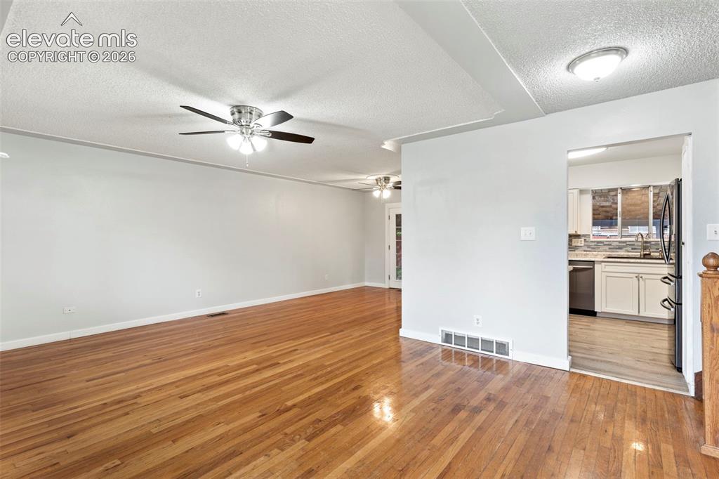 Image 14 of 36: Hardwood flooring throughout the main area and a ceiling fan