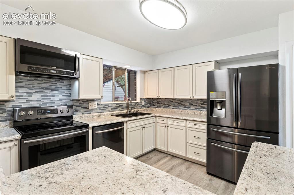 Image 15 of 36: Cream cabinetry, granite countertops, stainless steel appliances, tile back