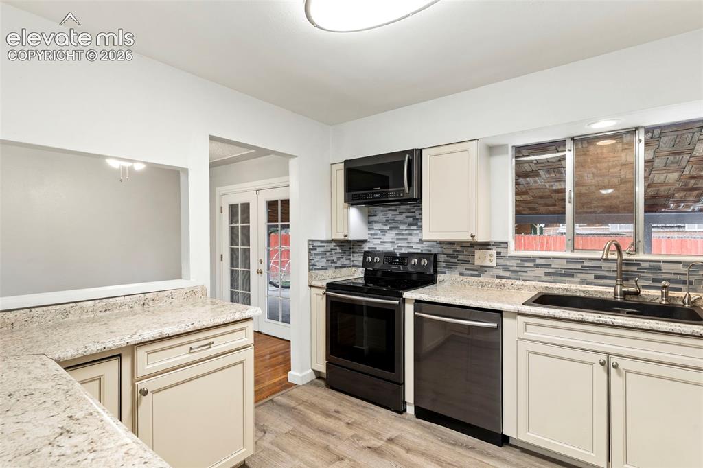 Image 16 of 36: Kitchen featuring light-toned cabinetry, speckled countertops, and a mosaic