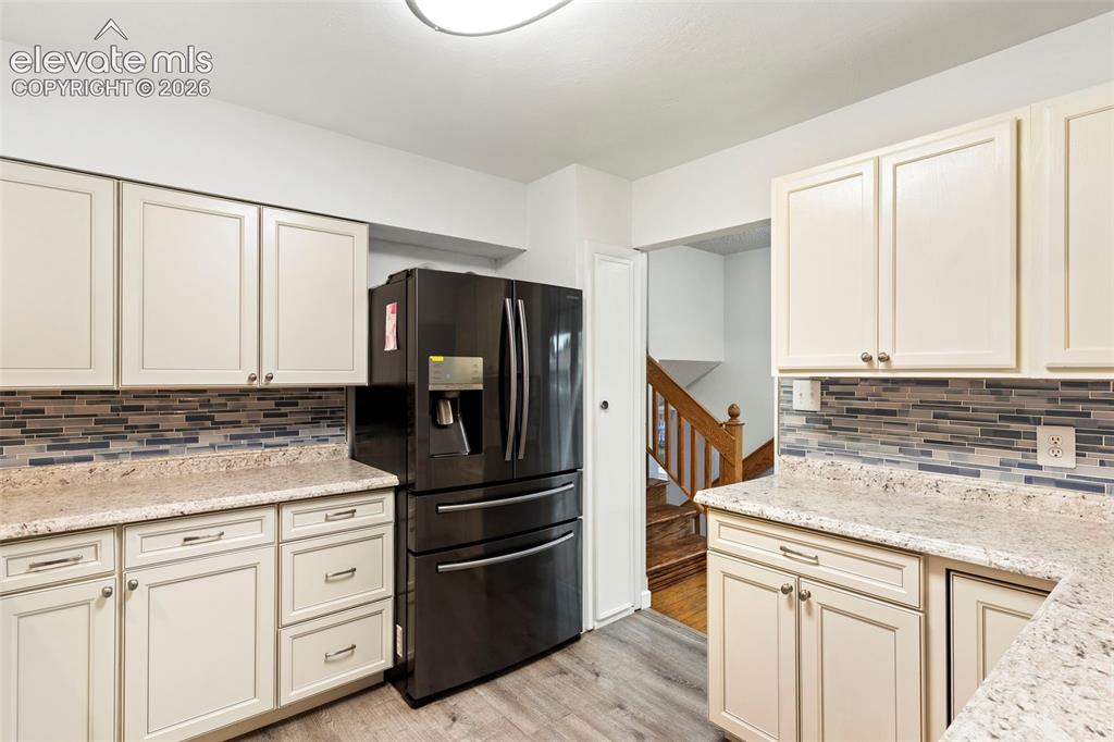 Image 17 of 36: Cream-colored cabinetry with modern hardware, stone-finish countertops, til
