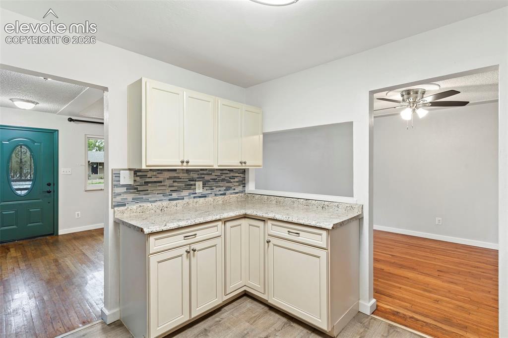 Image 18 of 36: Cream-toned cabinetry with dark hardware, speckled countertops, and a mosai