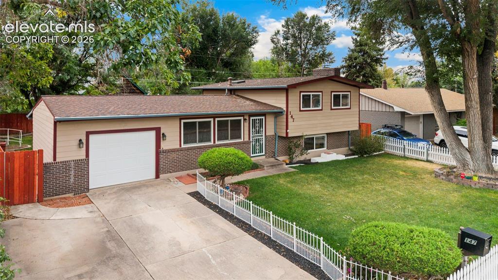 Image 2 of 36: Split-level residence featuring a two-car garage, concrete driveway, and fr