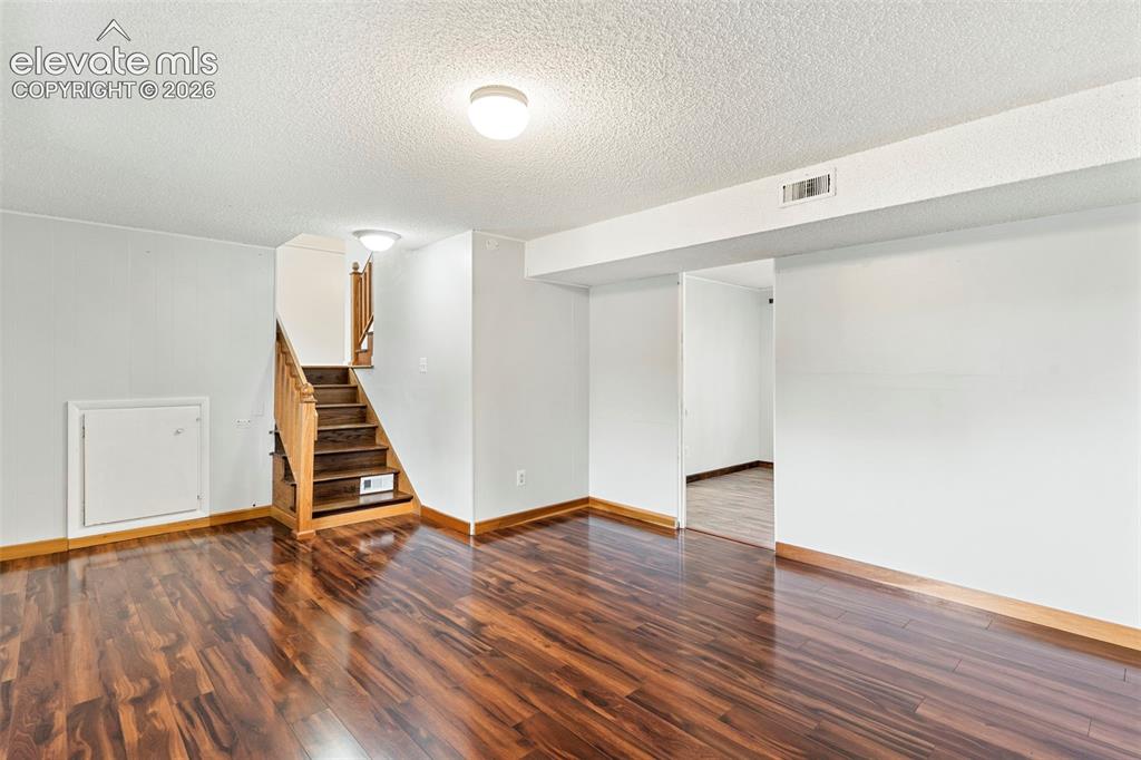 Image 20 of 36: Wood-finish flooring with coordinating wood trim, staircase with wood handr