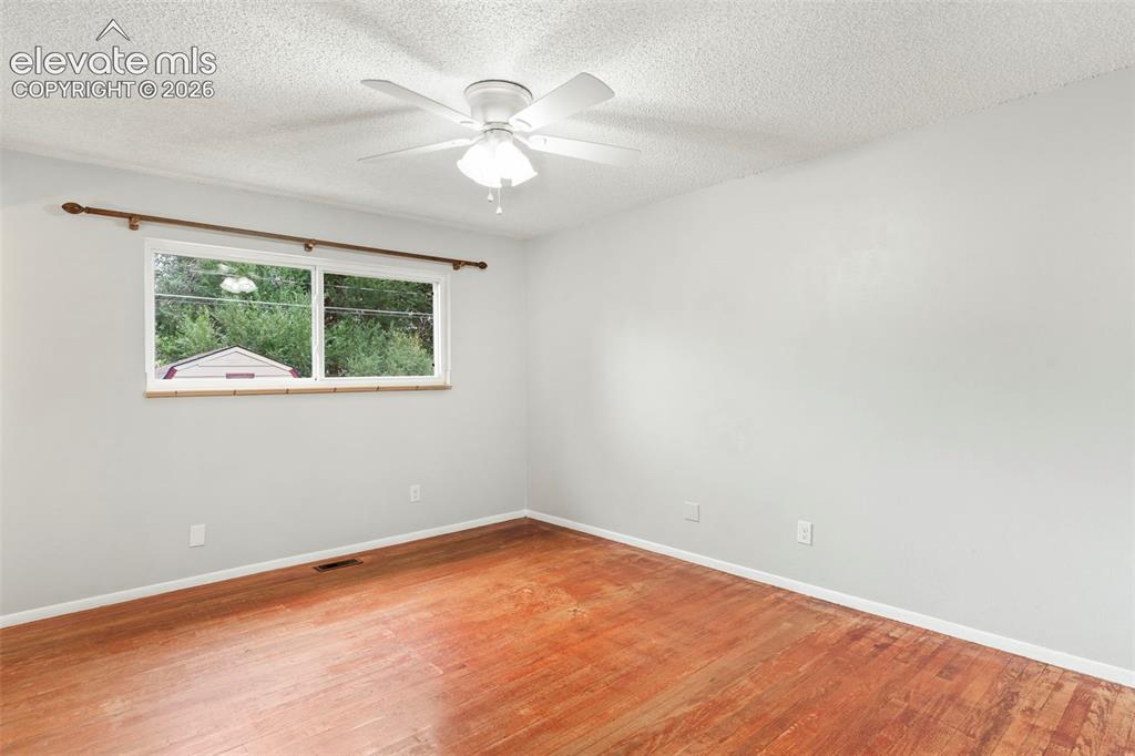 Image 22 of 36: Wood-finish flooring with light-toned walls and a white ceiling fan with li