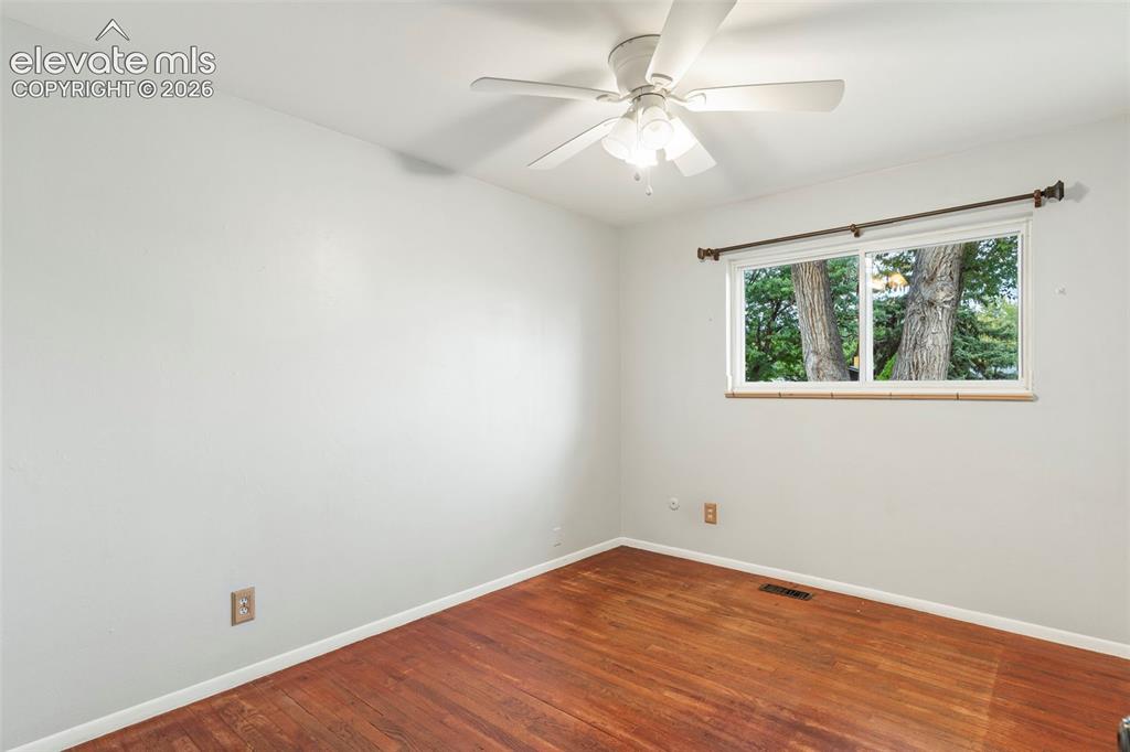 Image 25 of 36: Hardwood flooring, white painted walls, white ceiling fan, and a window wit