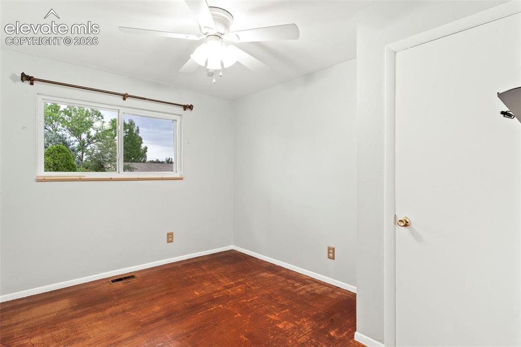 Image 28 of 36: Window with natural scenery, ceiling fan, white paneled door, wood-finish f