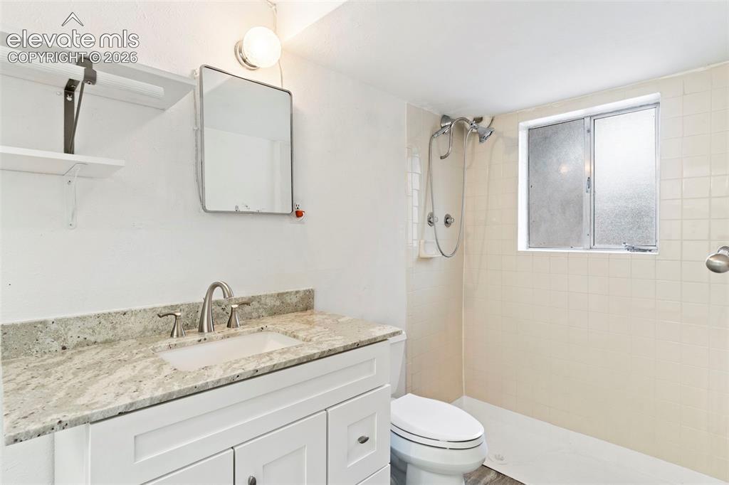 Image 30 of 36: White vanity with a light-toned countertop, undermount sink, and brushed ni