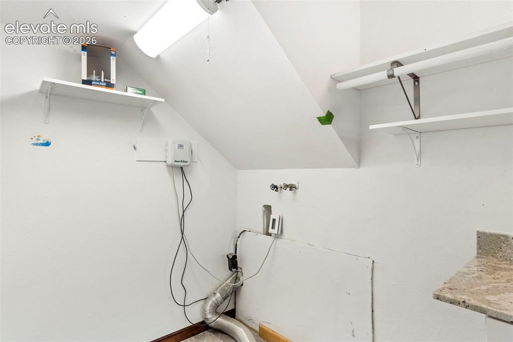 Image 32 of 36: Utility area featuring multiple storage shelves, a ceiling-mounted fluoresc
