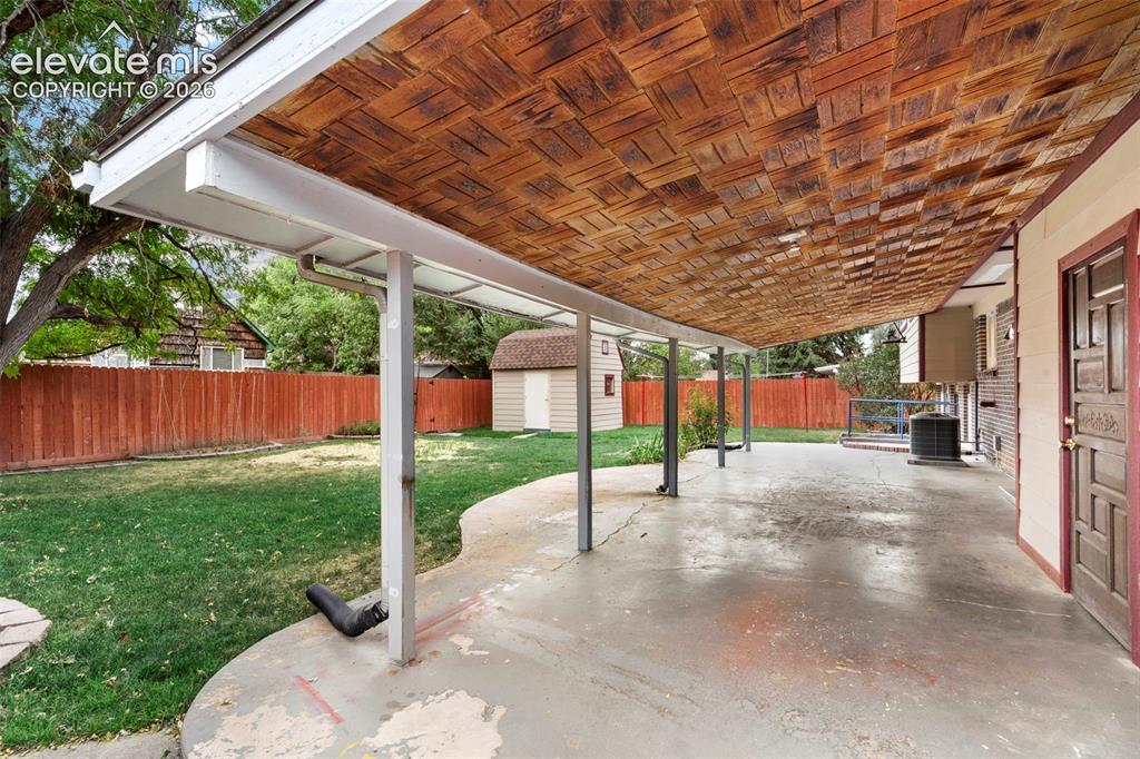 Image 33 of 36: Covered patio with a textured wood ceiling, offering expansive outdoor livi