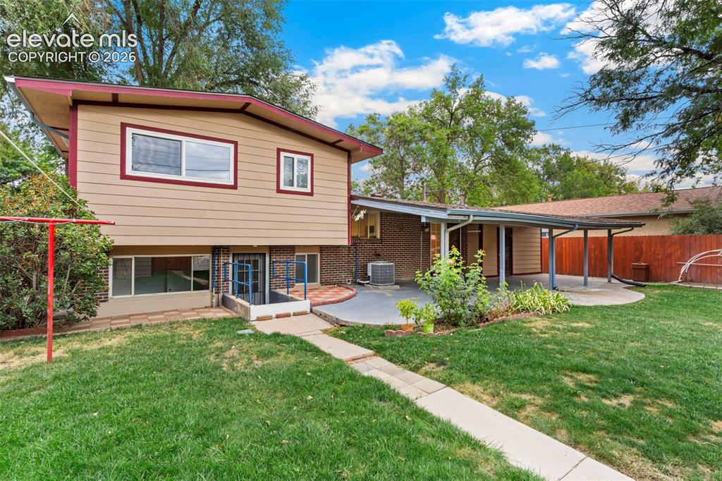 Image 35 of 36: Split-level residence featuring a covered patio, extensive lawn, concrete p