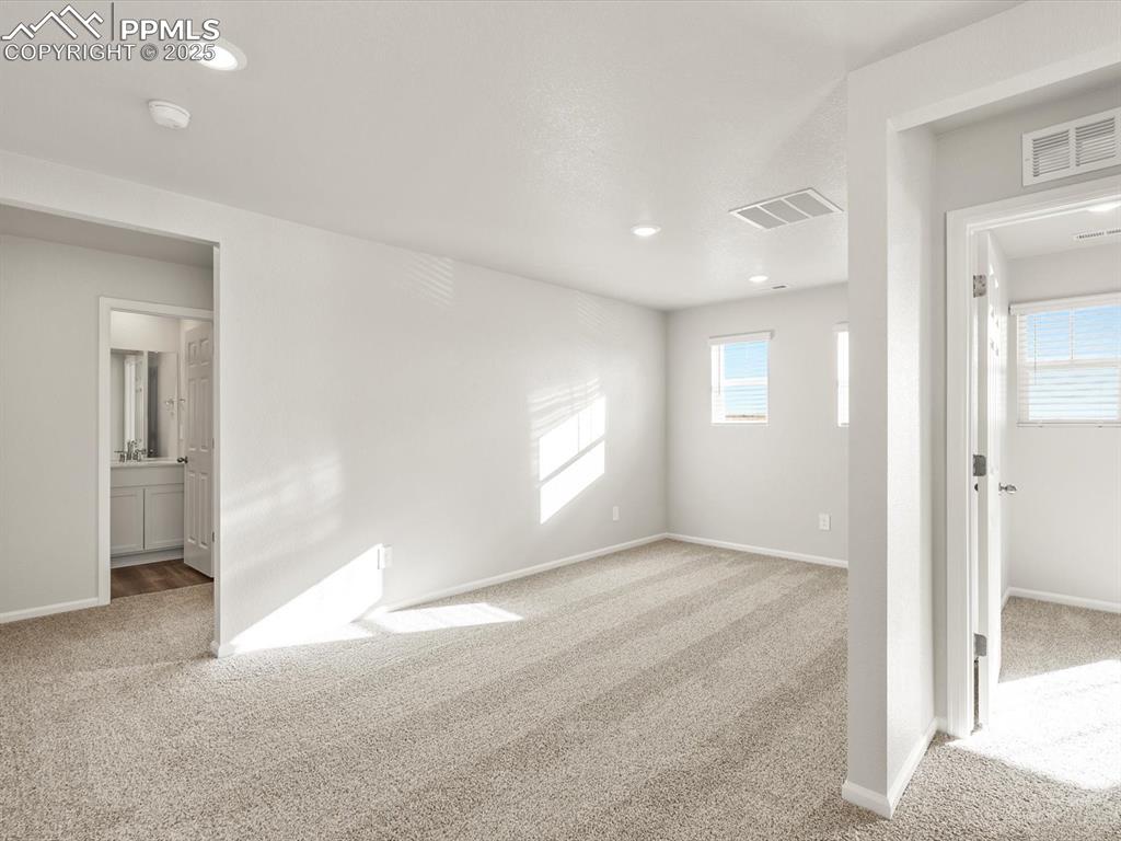 Image 13 of 26: Unfurnished bedroom with light carpet, multiple windows, recessed lighting,