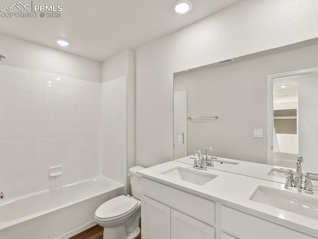 Image 18 of 26: Full bathroom with double vanity, tub / shower combination, dark wood-type